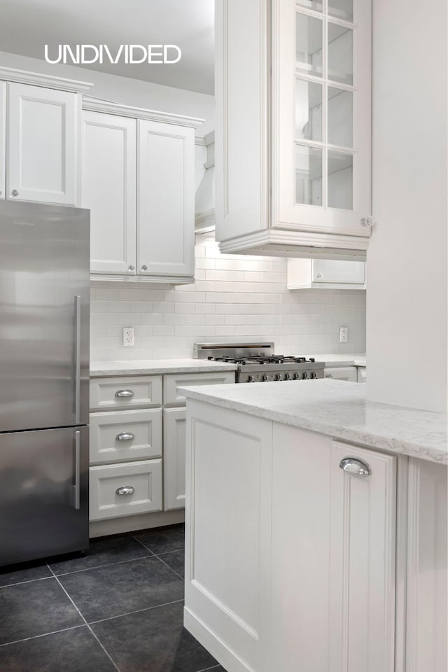 130 E 94th St Unit 2-E, New York City, NY 10128 - kitchen featuring freestanding refrigerator, backsplash, white cabinets, and dark tile patterned floors