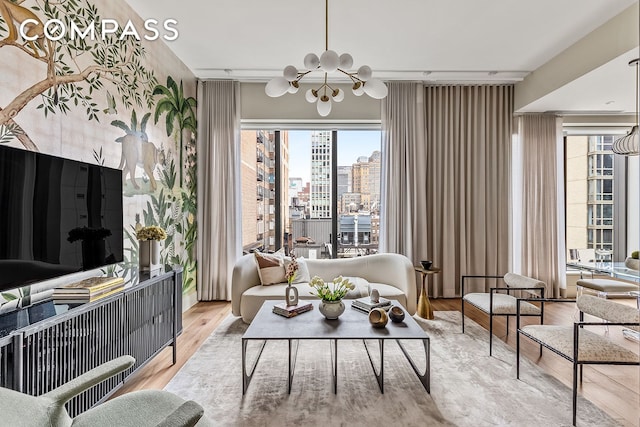 living area featuring plenty of natural light, wood finished floors, a chandelier, and a view of city