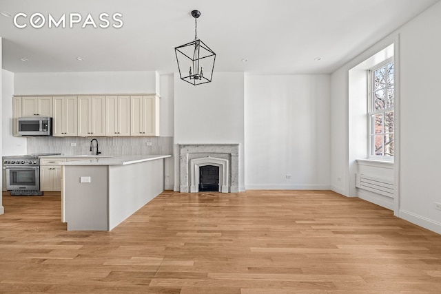 119 Henry St Unit 3, New York City, NY 11201 - kitchen with appliances with stainless steel finishes, a peninsula, a chandelier, light countertops, and decorative backsplash