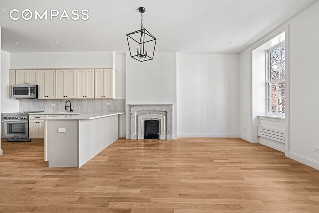 119 Henry St Unit 3, New York City, NY 11201 - kitchen with stainless steel appliances, a peninsula, a chandelier, light countertops, and tasteful backsplash