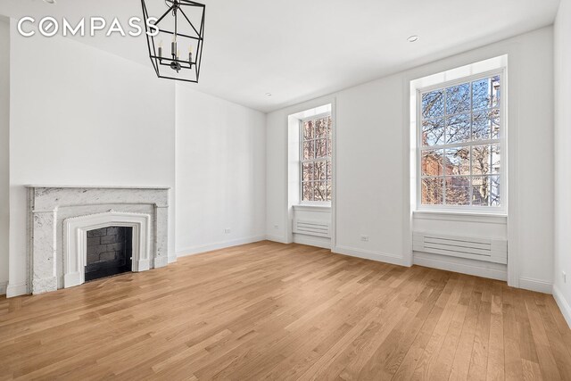 119 Henry St Unit 3, New York City, NY 11201 - unfurnished living room with wood finished floors, healthy amount of natural light, a chandelier, and baseboards