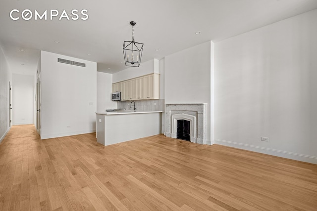 119 Henry St Unit 3, New York City, NY 11201 - unfurnished living room with a chandelier, light wood-type flooring, baseboards, and a fireplace
