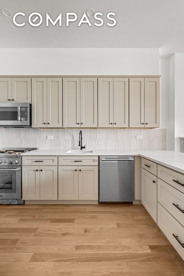 119 Henry St Unit 3, New York City, NY 11201 - kitchen featuring appliances with stainless steel finishes, a sink, light countertops, decorative backsplash, and light wood-type flooring