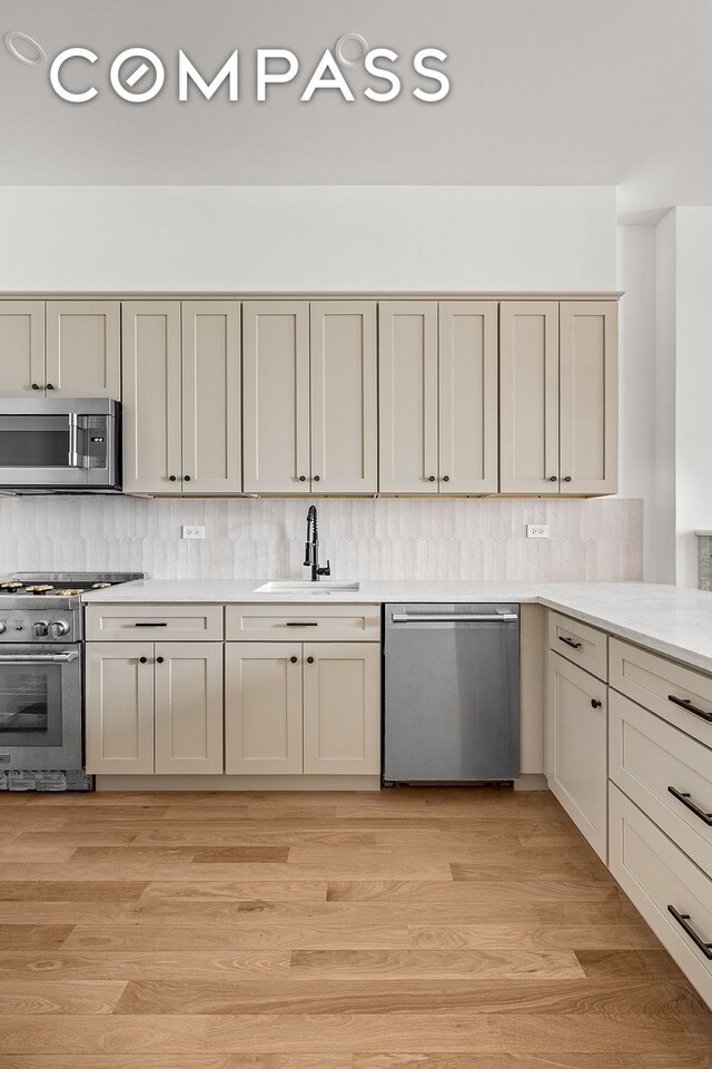 119 Henry St Unit 3, New York City, NY 11201 - kitchen featuring appliances with stainless steel finishes, a sink, light countertops, decorative backsplash, and light wood finished floors