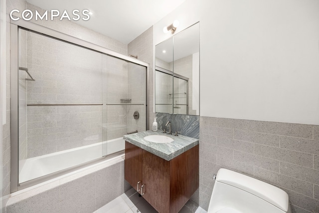 bathroom featuring tiled shower / bath, vanity, tile walls, toilet, and tile patterned flooring