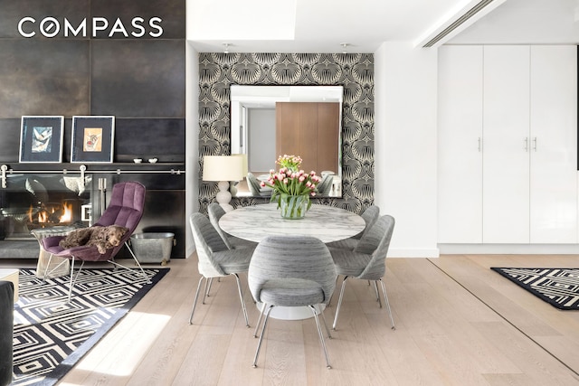 dining space with wallpapered walls and wood finished floors