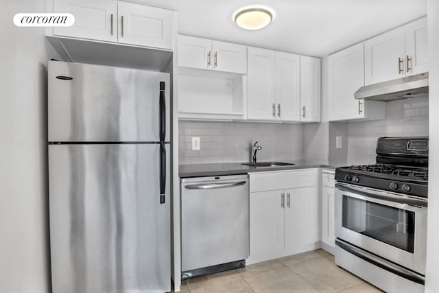 kitchen with stainless steel appliances, under cabinet range hood, a sink, and white cabinetry
