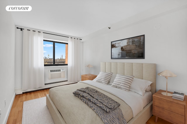 bedroom with wood finished floors, an AC wall unit, and a baseboard radiator