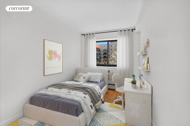 bedroom featuring wood finished floors and a baseboard heating unit
