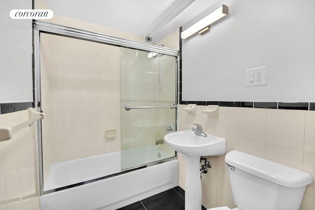 full bath with toilet, shower / bath combination with glass door, tile walls, and tile patterned floors