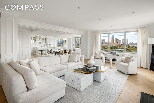 living area featuring crown molding, a decorative wall, and a city view