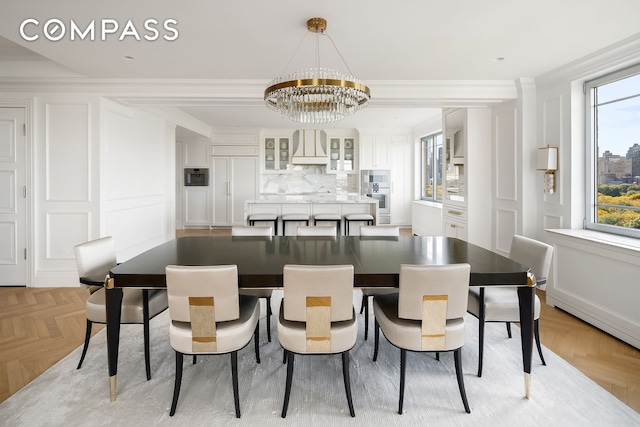 dining space with a chandelier, a healthy amount of sunlight, crown molding, and a decorative wall
