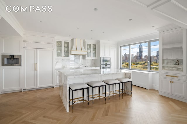 kitchen featuring a center island, a kitchen breakfast bar, white cabinets, and premium range hood