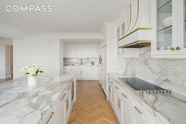 kitchen with premium range hood, white cabinets, light stone counters, and black electric stovetop