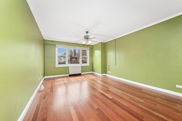 spare room with crown molding, radiator heating unit, hardwood / wood-style flooring, and baseboards