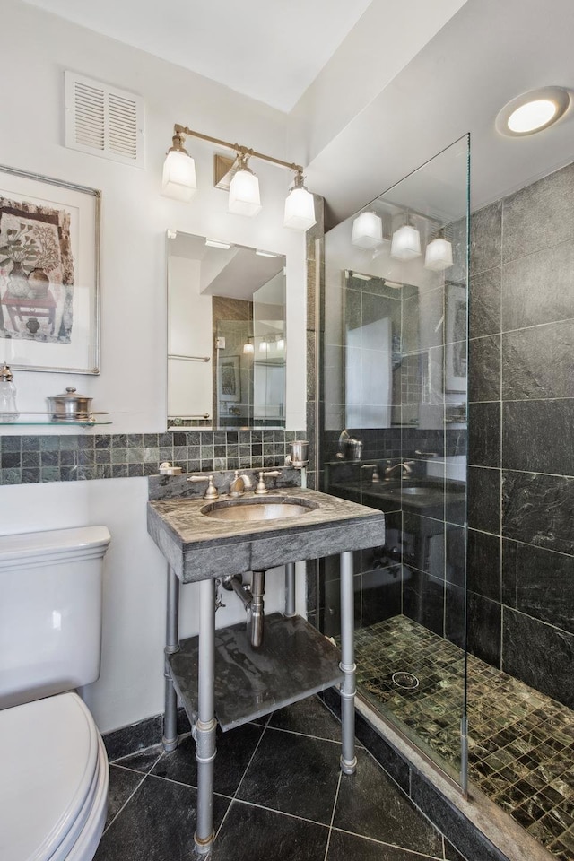 115 E 87th St Unit 18A, New York City, NY 10128 - bathroom featuring tile walls, a sink, a shower stall, toilet, and visible vents