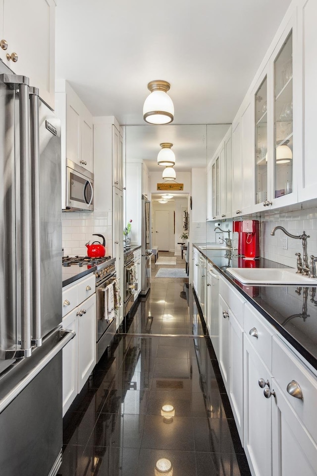 115 E 87th St Unit 18A, New York City, NY 10128 - kitchen featuring white cabinets, high end appliances, decorative backsplash, and a sink