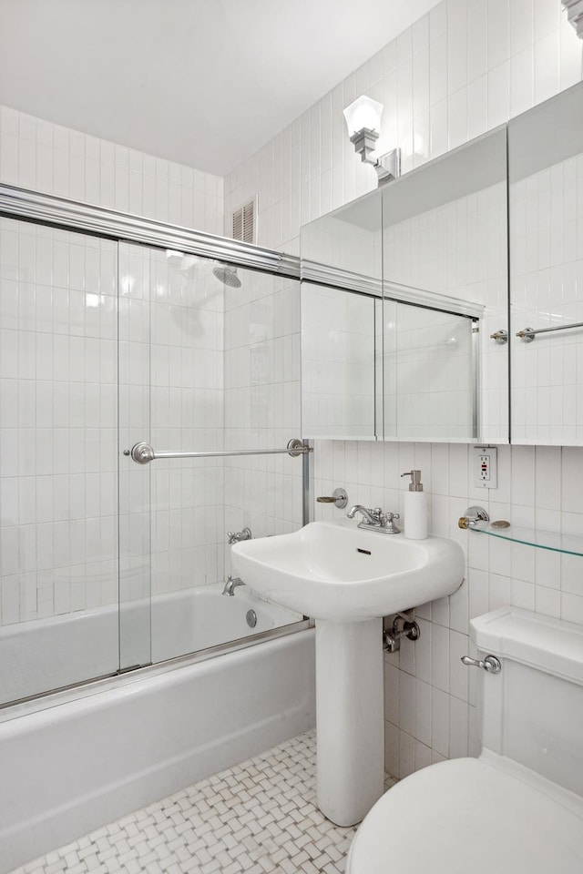 115 E 87th St Unit 18A, New York City, NY 10128 - full bath featuring enclosed tub / shower combo, toilet, backsplash, and tile walls
