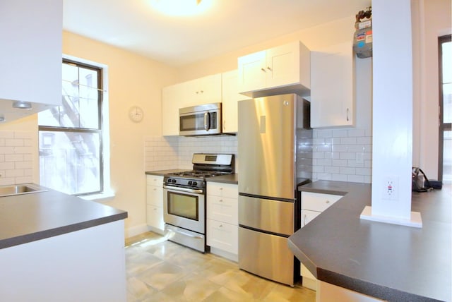 kitchen with stainless steel appliances, white cabinets, backsplash, and dark countertops