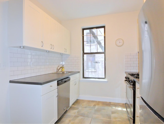 kitchen featuring gas range, dishwasher, a sink, dark countertops, and freestanding refrigerator
