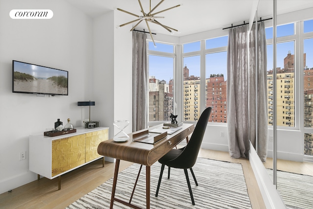 home office with light wood-type flooring, a city view, and a healthy amount of sunlight