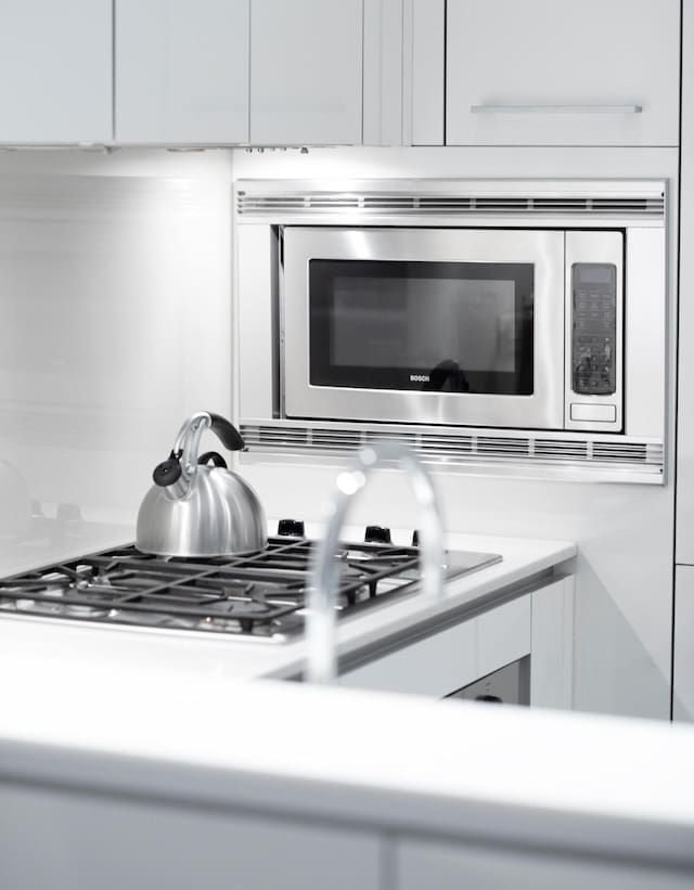 kitchen view of appliances with stainless steel finishes, white cabinets, and light countertops