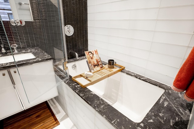 bathroom with a bathtub, tile walls, a shower, and vanity