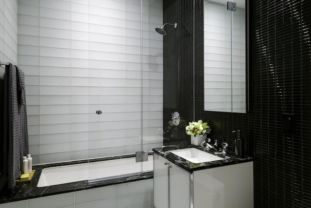 bathroom with vanity, tiled shower / bath, and tile walls