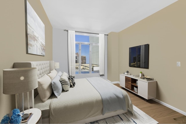 bedroom featuring wood finished floors, baseboards, and access to outside