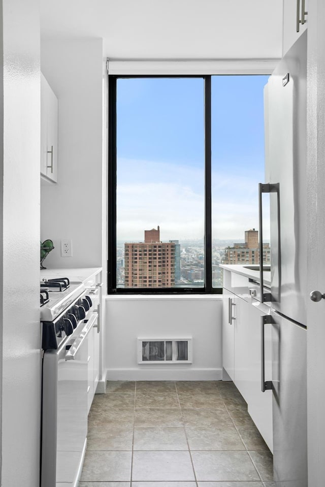 kitchen featuring white cabinets, gas stove, and freestanding refrigerator