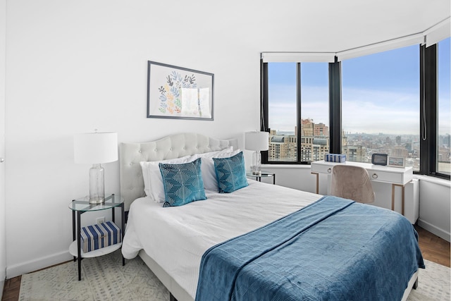 bedroom featuring wood finished floors, baseboards, and a view of city