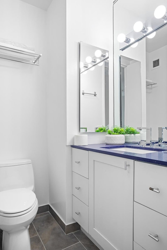 bathroom featuring vanity, toilet, tile patterned floors, and baseboards