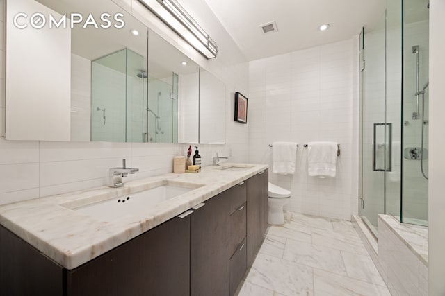 101 Warren St Unit 590, New York City, NY 10007 - bathroom with tile walls, double vanity, a stall shower, marble look tile flooring, and recessed lighting