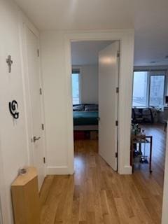 hall with light wood-style floors and baseboards