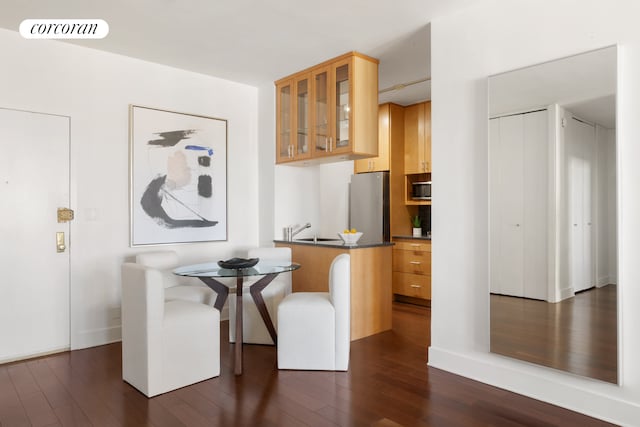 58 W 58th St Unit 24B, New York City, NY 10019 - kitchen featuring stainless steel appliances, dark wood-type flooring, glass insert cabinets, dark countertops, and a peninsula