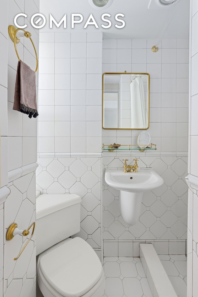 bathroom with toilet, a shower with shower curtain, and tile walls