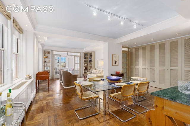 dining area with rail lighting, crown molding, and built in features