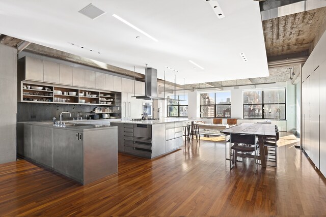 205 W 19th St Unit 11, New York City, NY 10011 - kitchen with wall chimney range hood, modern cabinets, dark wood-style floors, gray cabinetry, and a kitchen island
