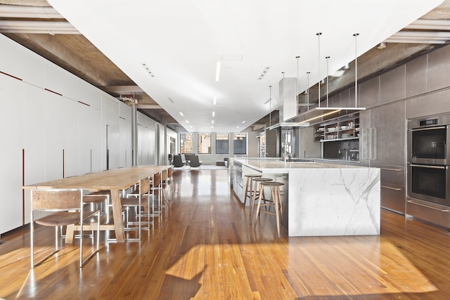 205 W 19th St Unit 11, New York City, NY 10011 - kitchen featuring modern cabinets, double oven, a spacious island, wood-type flooring, and a sink