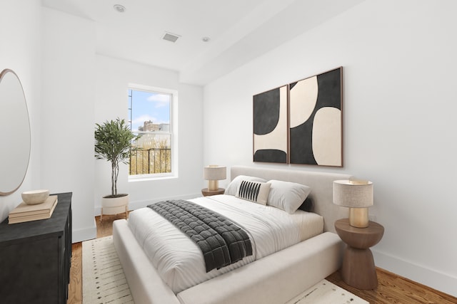 bedroom with wood finished floors, visible vents, and baseboards