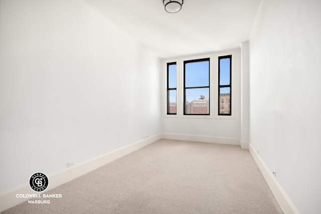unfurnished room with baseboards and light carpet