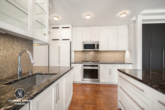 420 Riverside Dr Unit 12H, New York City, NY 10025 - kitchen featuring appliances with stainless steel finishes, a sink, tasteful backsplash, white cabinetry, and dark stone counters