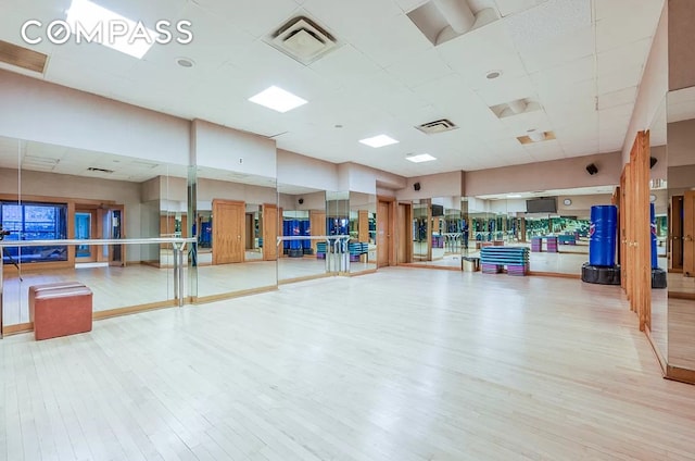 exercise room featuring wood finished floors and a drop ceiling