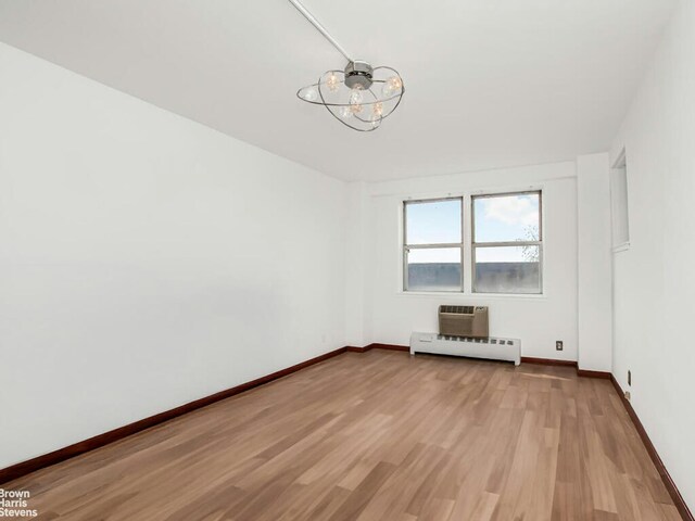 5800 Arlington Ave Unit 7L, New York City, NY 10471 - spare room featuring a baseboard radiator, a chandelier, light wood finished floors, baseboards, and a wall unit AC