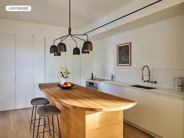 9 Chapel St Unit 5C, New York City, NY 11201 - kitchen with a sink, black electric stovetop, butcher block counters, a breakfast bar, and white cabinetry