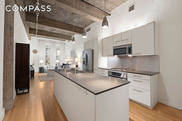 419 W 55th St Unit 2D, New York City, NY 10019 - kitchen with a sink, stainless steel appliances, dark countertops, and light wood-style floors