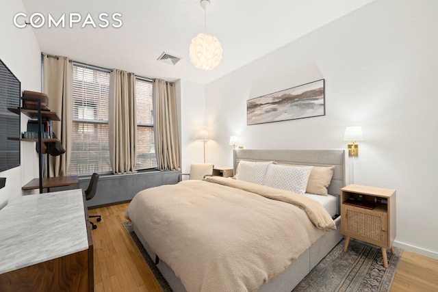 bedroom featuring baseboards, wood finished floors, and visible vents
