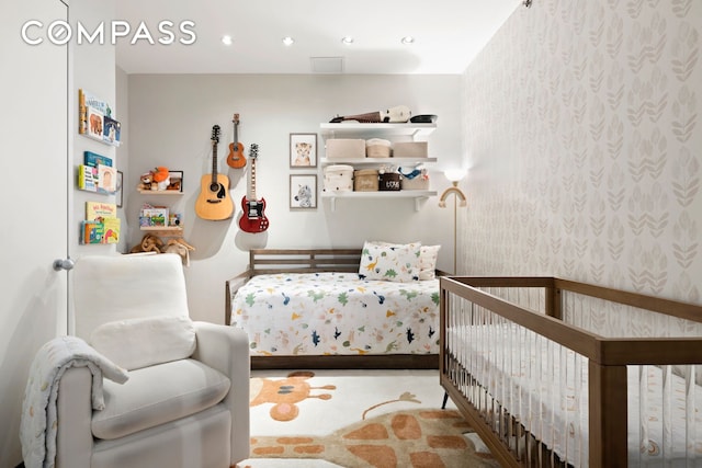 bedroom featuring wallpapered walls and a nursery area