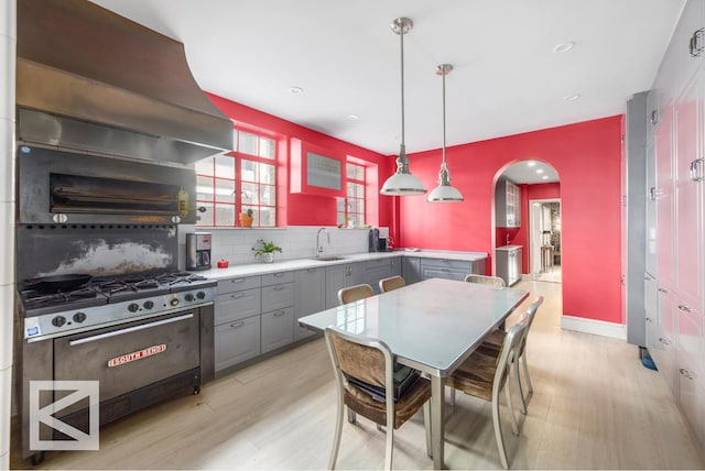 115 E 67th St Unit 3D/4D, New York City, NY 10065 - kitchen with gray cabinetry, arched walkways, a sink, tasteful backsplash, and custom exhaust hood