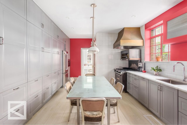 115 E 67th St Unit 3D/4D, New York City, NY 10065 - kitchen featuring a sink, wall chimney exhaust hood, gray cabinets, stainless steel appliances, and light wood-style floors